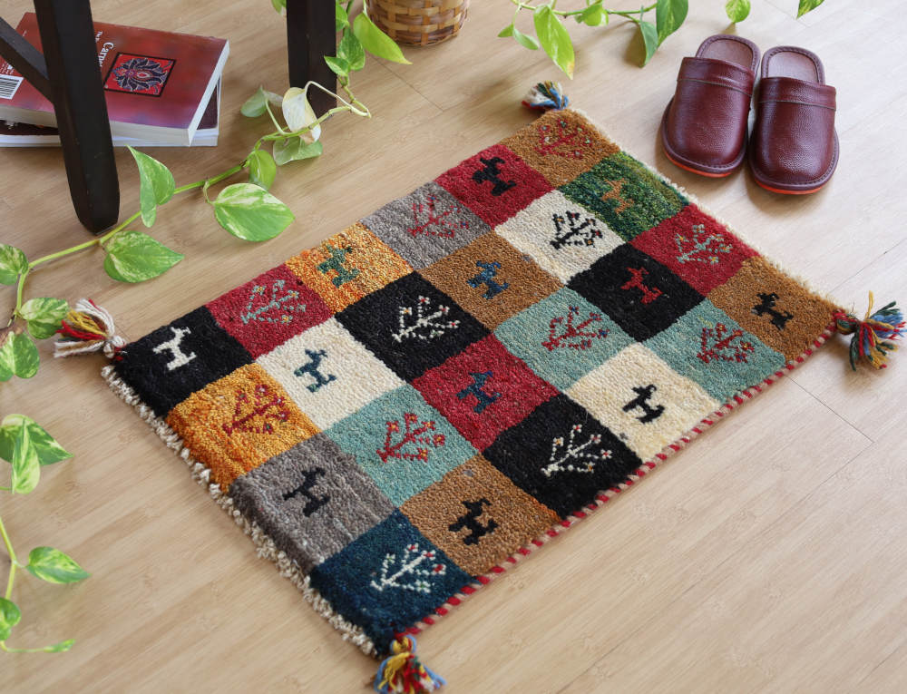 カラフルなチェス模様のミニギャッベ（59×41cm）を椅子の足元に敷いたところ